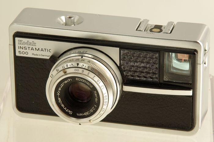 Instamatic 500
Période de production : 1963-1965 - Allemagne - n° 74923
Type : compact
Format : 28x28 mm sur chargeur 126
Viseur : clair collimaté avec aiguille du posemètre
Objectif : Xenar rétractable de 1:2,8 f=38 mm - mise au point de 0,70 m à l'infini
Mesure de l'exposition : posemètre sélénium Gossen
Réglages : diaphragmmes (2,8-22) et vitesses
Sensibilité du film : 25 à 200 ASA
Obturateur : central Compur de 1/30 s à 1/5000 s + B - 1/125 s avec flash
Déclencheur : sur le capot avec embout fileté
Griffe : oui
Synchronisation : prise coaxiale en façade
Ecrou de pied : oui
Avance du film et armement : levier à une seule manoeuvre dans la semmelle
Ouverture du dos : par poussoir sur le côté
Alimentation du flash : sans
Dimensions : 122 x 67 x 58 mm
Poids : 415 g Instamatic_500.jpg