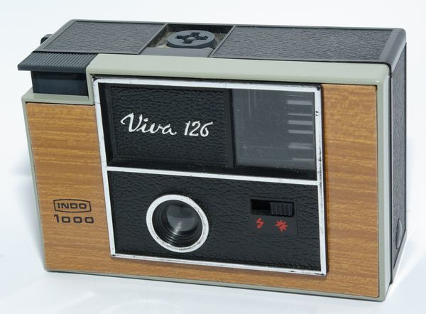 Viva 126 1000 version 12
Période de production : 1975 - France
Variations : décor bois - façade chromée - anneau de dragonne étroit - petit verre
sérigraphie vers l'objectif - levier d'armement court - presse-film bleu
Format : 28 x 28 mm sur chargeur 126
Viseur : clair
Objectif : ménisque plastique - mise au point fixe de 1,2 m à l'infini
Mesure de l'exposition : sans
Réglages : soleil et flash
Obturateur : central à secteur sans armement préalable
Déclencheur : sur le capot
Flash : griffe pour Flashcube
Ecrou de pied : non
Armement : levier à une seule manoeuvre
Ouverture du dos : par poussoir sur le côté
Alimentation : 2 pile AA de 1,5 v
Dimensions : 118 x 73 x 54 mm
Poids : 164g Indo Viva 126 1000 v12 38.jpg